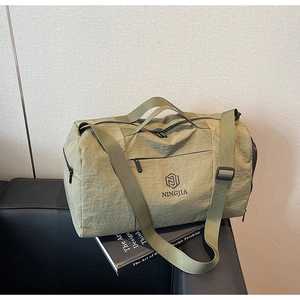 Detail of green nylon travel bag with handles and adjustable strap on a sofa