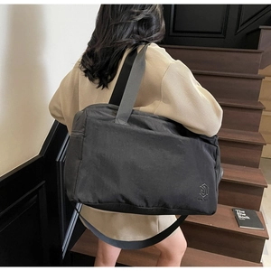 Detail of large black travel bag with side zipper and strap on a wooden staircase