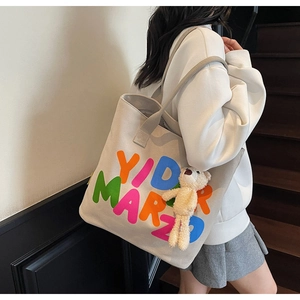 Detail of canvas tote bag featuring YID MARZO lettering and a cute plush bear charm