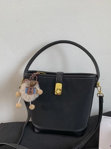 Borsa a secchiello nera minimalista con chiusura dorata e ciondolo a forma di pecora