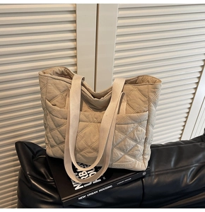 Detailed view of beige quilted tote bag with diamond stitching and leather base