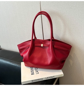 Detail of red lychee grain leather tote bag with elegant pleats and golden metal buckle