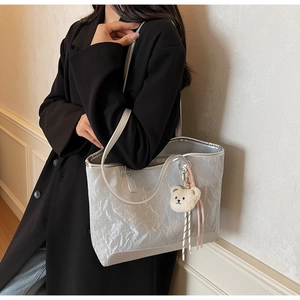 Detail of silver metallic tote bag with crinkled texture and plush bear charm