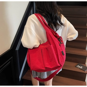 Red large capacity nylon crossbody bag with adjustable wide strap and side brand logo label