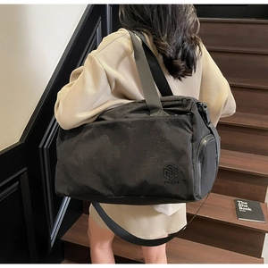 Detail of black waterproof travel bag featuring a side pocket and adjustable fabric strap