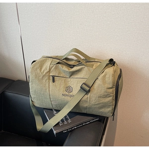 Close-up of olive green travel bag with logo detail on a textured leather sofa