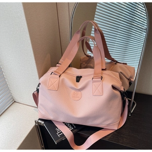 Detailed close-up of a pink travel bag featuring reinforced handles and a sturdy shoulder strap