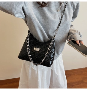 Detail of black quilted bucket bag featuring a silver twist lock and woven chain strap