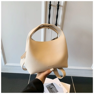 Detailed macro view of the beige lychee pattern PU leather and brand logo on bucket bag