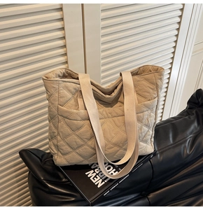 Detail view of quilted puffer tote bag with wide shoulder strap and side pocket