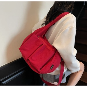 Detail view of large red canvas crossbody bag with double front pockets on female model