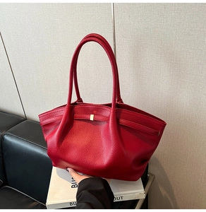 Detail of red lychee grain leather tote bag featuring gold buckle and retro pleat design