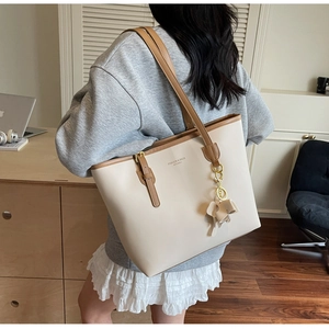 Detail showing beige and brown PU leather tote bag with elephant charm and shoulder strap