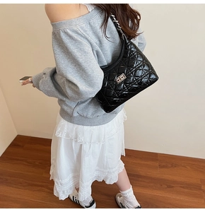 Detail of black quilted leather bucket bag with silver chain strap and metal swivel lock