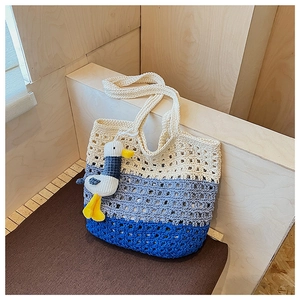 Detailed close-up of handmade crochet tote bag with blue and beige stripes and charm
