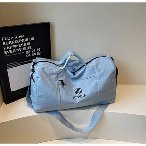 Detail view of light blue travel bag with waterproof compartments and shoulder strap