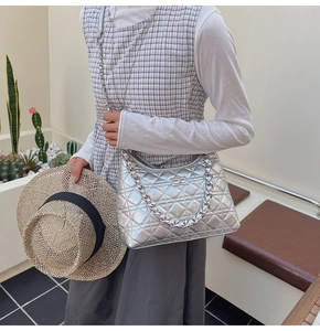 Detail of silver quilted bucket bag featuring a thick metal chain and twist-lock clasp