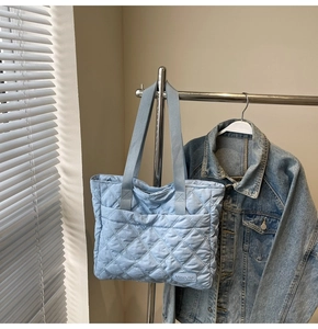 Close-up of sky blue quilted tote bag with diamond pattern and woven brand label