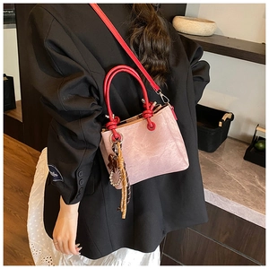 Detail of pink faux suede bucket bag with red handles and decorative tassels