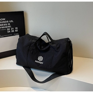 Close-up of black travel bag showing front logo, side zipper pocket and nylon material