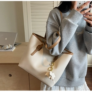 Detail of large tote bag with elephant charm and contrast trim shown in office setting