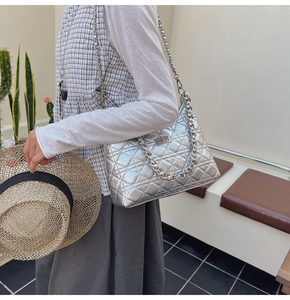 Detailed view of silver quilted bucket bag with metallic finish and heavy chain strap