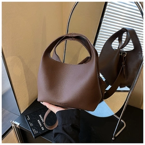 Detail view of coffee-colored lychee leather bucket bag showing embossed logo and texture
