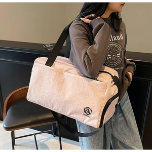 Detail of pink travel bag with black strap worn by a woman in a minimalist room