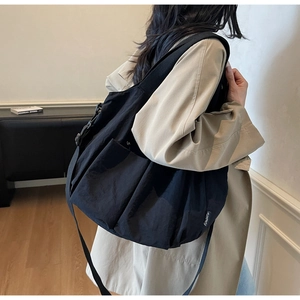Lifestyle view of large black nylon tote bag with adjustable strap and side pockets