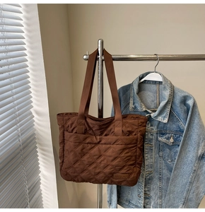 Close-up of brown quilted nylon tote bag with wide strap hanging on a metal hanger