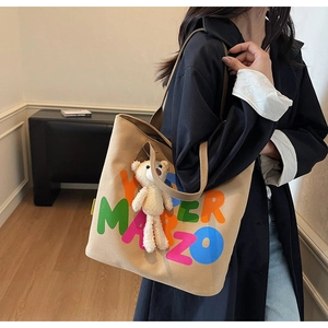 Detail of canvas tote bag with colorful letters and a detachable white plush bear charm
