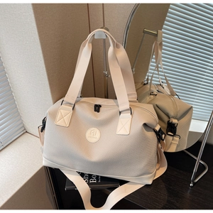 Detailed close-up of a beige textured travel bag with brand logo and adjustable strap