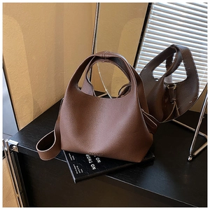 Detailed view of dark brown pebbled leather bucket bag with top handle and logo