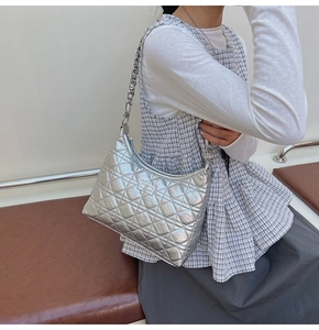 Detail view of silver quilted leather shoulder bag with metallic chain and lock