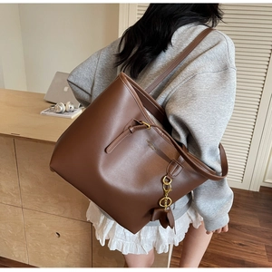 Close-up of brown leather tote bag with fashion logo and golden elephant charm