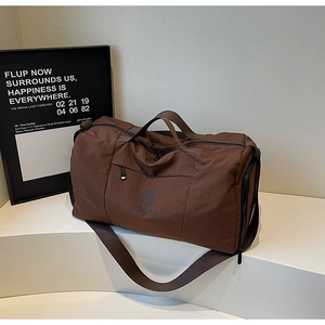 Brown travel duffel bag with dual handles and adjustable shoulder strap on white platform