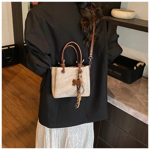 Back view of a model wearing a vintage beige crossbody bucket bag with brown tassel