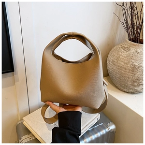Detail of beige litchi grain leather bucket bag with wide shoulder strap and top handle