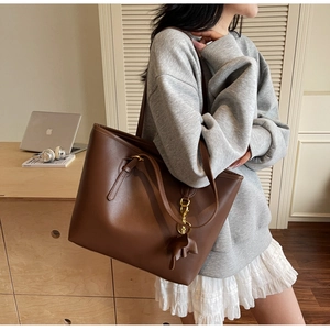 Brown leather tote bag featuring a cute elephant charm on a minimalist shoulder strap