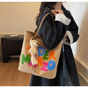 Detailed view of beige canvas tote bag with colorful letters worn by a model