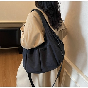 Detail view of large capacity black nylon crossbody bag with pleated texture and side pocket