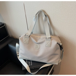 Detail of light grey travel bag with leather logo patch and adjustable woven shoulder strap