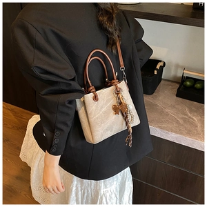 Retro cream leather bucket bag with brown handles shown on a model in a professional outfit
