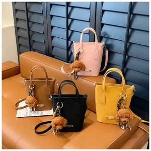 Détail de quatre sacs seaux colorés avec breloques doudou sur un canapé en cuir