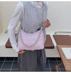 Detail of pink quilted shoulder bag featuring silver chain and metal twist lock closure
