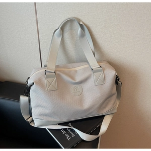 Detail of grey travel bag featuring high-density twill fabric and durable rubber logo