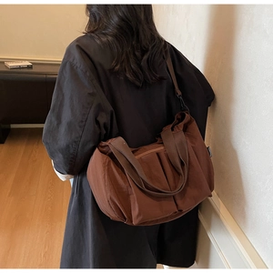 Brown large-capacity nylon tote bag with adjustable strap worn on female model's shoulder