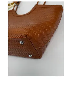 Détail du fond d'un sac cabas tressé marron avec des clous en métal argenté et tissage