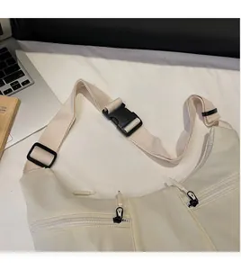 Detail view of the wide adjustable shoulder strap with plastic buckle on a beige dumpling bag