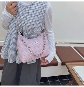 Detail of light pink quilted leather texture with silver chain strap and metal turn-lock